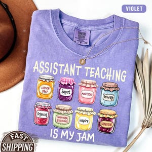 Puede incluir: Camiseta morada con el texto "Assistant Teaching is my jam" y un gr&aacute;fico de tarros de mermelada con palabras como "Lesson Prep", "Support", "Monitoring", "Encourage", "Organizing", "Behavioral Strategies", "Inspire" y "Supervising" en los tarros.