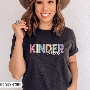 May include: Dark grey heather t-shirt with the text "Kinder Crew" in rainbow colors.
