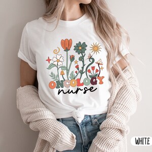 May include: White t-shirt with a floral design and the text "ONCOLOGY nurse".