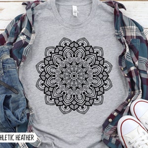 May include: A heather grey t-shirt with a black and white mandala design. The text "ATHLETIC HEATHER" is printed on the bottom of the shirt.