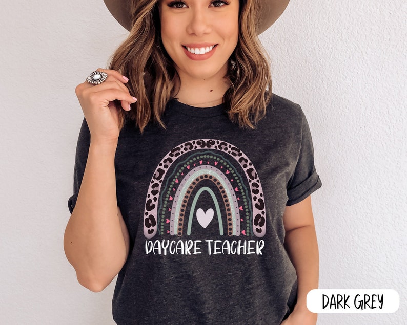 May include: Dark grey t-shirt featuring a rainbow design and the text "Daycare Teacher". The rainbow is made of leopard print and has a white heart in the centre.