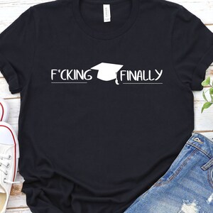 May include: Black t-shirt with white text that reads "F*CKING FINALLY" and a graduation cap graphic.