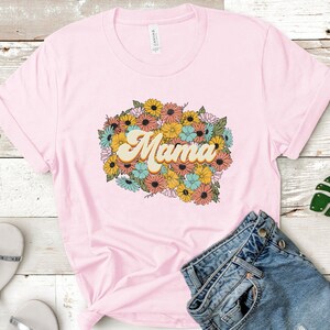 Puede incluir: Camiseta rosa con un dise&ntilde;o floral y la palabra "Mama" en una fuente retro.