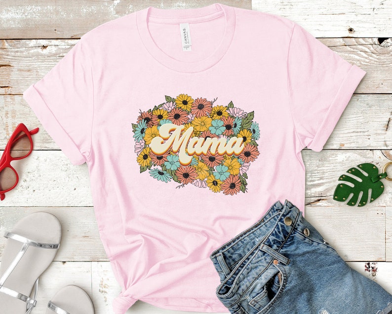 Puede incluir: Camiseta rosa con un dise&ntilde;o floral y la palabra "Mama" en una fuente retro.