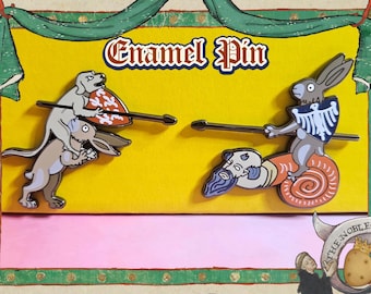 May include: Enamel pin featuring two medieval-style illustrations of animals in combat. One shows a dog and rabbit, the other a rabbit riding a snail. The text "Enamel Pin" is at the top.