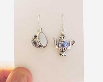 Puede incluir: Un par de pendientes de plata con abalorios de porcelana azul y blanca. Un abalorio es una taza de té y el otro es una tetera.
