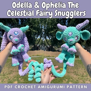 May include: A crochet pattern for two amigurumi fairy plushies named Odella and Ophelia. The fairies are purple and teal with long tails and are holding hands. The pattern is called "Celestial Fairy Snugglers" and is a PDF crochet amigurumi pattern.