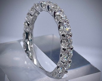 Könnte beinhalten: Ein silberner Ring mit einer Reihe von funkelnden Diamanten in Pavé-Fassung.