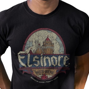 May include: Black t-shirt with a distressed graphic of a castle inside an oval. The graphic includes the word "Elsinore" in a vintage font, along with "Beer-Bière" and "Product of Canada".