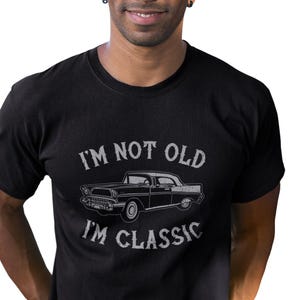 May include: A black t-shirt featuring a vintage car graphic and the text "I'm not old I'm classic".