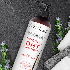 May include: A brown bottle of Shiny Leaf Original DHT Conditioner with an active formula. The bottle has a black pump top and a white label with black text. The text on the label reads "Shiny Leaf", "Active Formula", "Original DHT Conditioner", "For Men & Women", and "With Fruit Extract, Natural Oils, and Biotin".