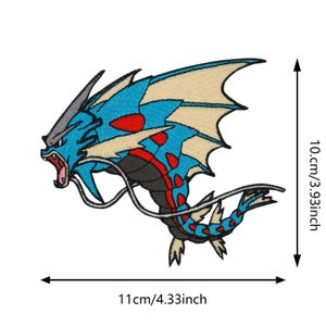 May include: Embroidered patch of a blue, red, and tan mythical creature with an open mouth. The patch is 11cm wide and 10cm tall. The creature has a long tail and large wings.