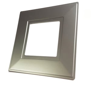 May include: A silver square wall plate with a rectangular cutout in the centre. The plate has a slightly raised edge around the cutout.