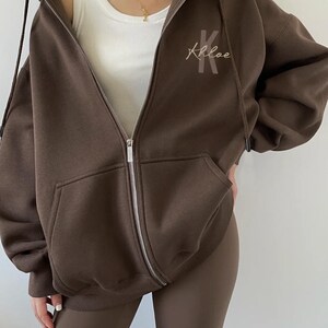 May include: A brown oversized zip-up hoodie with a large "Khloe" embroidered on the front.