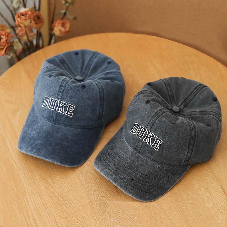 May include: Two blue denim baseball caps with the word "DUKE" embroidered in white on the front.