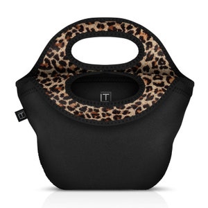 Puede incluir: Bolsa de almuerzo negra con ribete de estampado de leopardo. La bolsa tiene un asa superior y un cierre de cremallera.