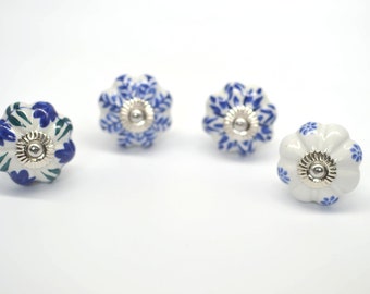 May include: Four ceramic cabinet knobs with a white base and blue and green floral designs. Each knob has a silver metal accent in the centre.
