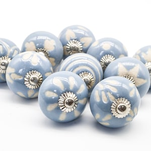 May include: Ten blue ceramic cabinet knobs with white floral designs and silver accents.