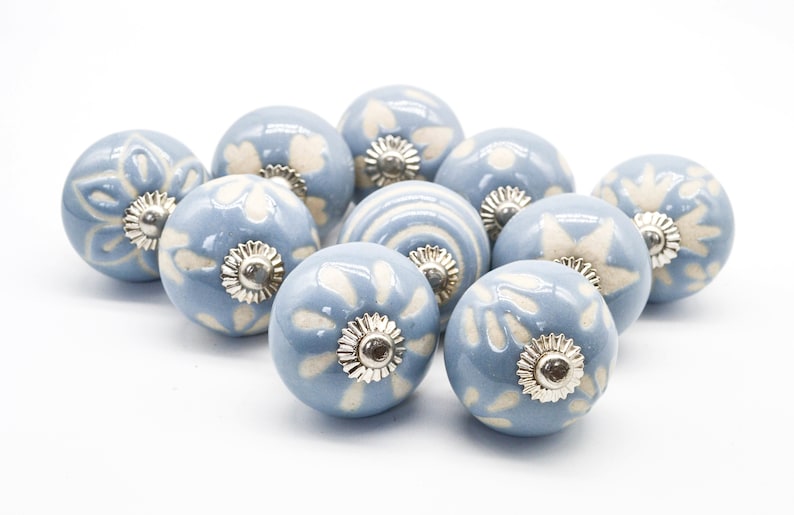 May include: Ten blue ceramic cabinet knobs with white floral designs and silver accents.