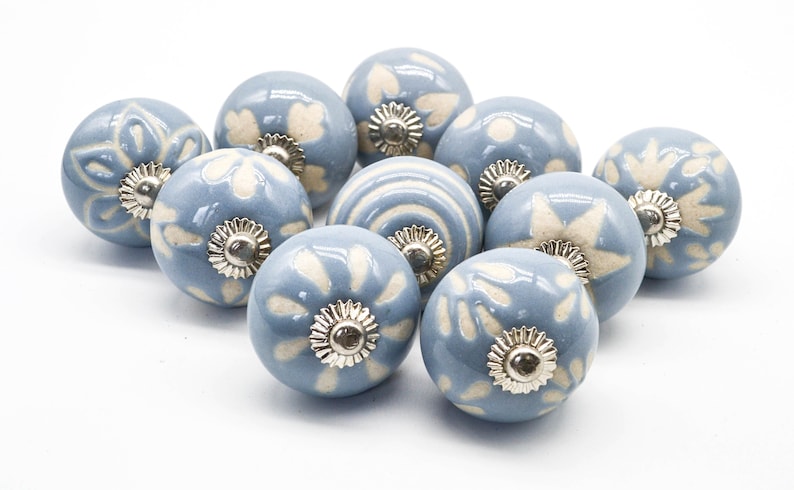 May include: A set of ten blue ceramic cabinet knobs with white floral designs. Each knob has a silver metal base.