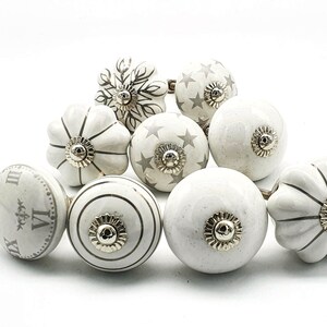 以下が含まれることがあります： 星、ストライプ、時計の文字盤など、さまざまなデザインが施された白いセラミック製のキャビネットノブ10個のセット。ノブはシルバー仕上げで、どんな部屋にもエレガントな雰囲気を添えるのに最適です。