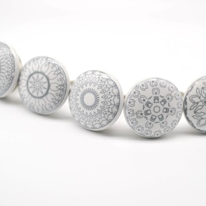 Puede incluir: Cinco pomos de armario de cerámica blanca con diseños de mandala grises.