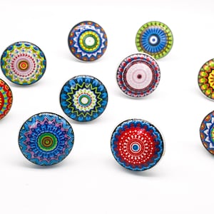 以下が含まれることがあります： マンダラ模様のカラフルなセラミックノブが9個。ノブは丸型で、白地に赤、青、緑、黄、オレンジの複雑な模様が施されています。