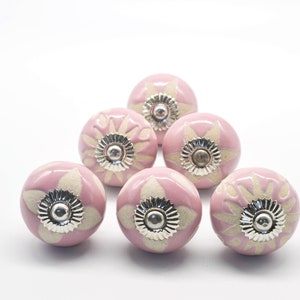 May include: Set of seven pink ceramic cabinet knobs with a white floral design and silver accents.