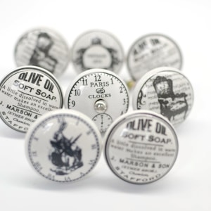 以下が含まれることがあります： 白地に黒と白のヴィンテージデザインが施されたセラミック製のノブが8個。デザインには、時計の文字盤、椅子、オリーブオイル石鹸のボトルが含まれています。