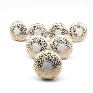May include: Set of six white ceramic cabinet knobs with a gold filigree design.