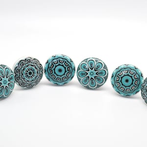 May include: Six turquoise and black ceramic cabinet knobs with intricate mandala designs.