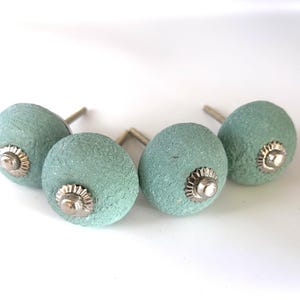 Puede incluir: Cuatro pomos de armario de color aguamarina con un acabado texturizado. Cada pomo tiene una base plateada y un centro decorativo plateado. Los pomos est&aacute;n dise&ntilde;ados para muebles y decoraci&oacute;n del hogar.