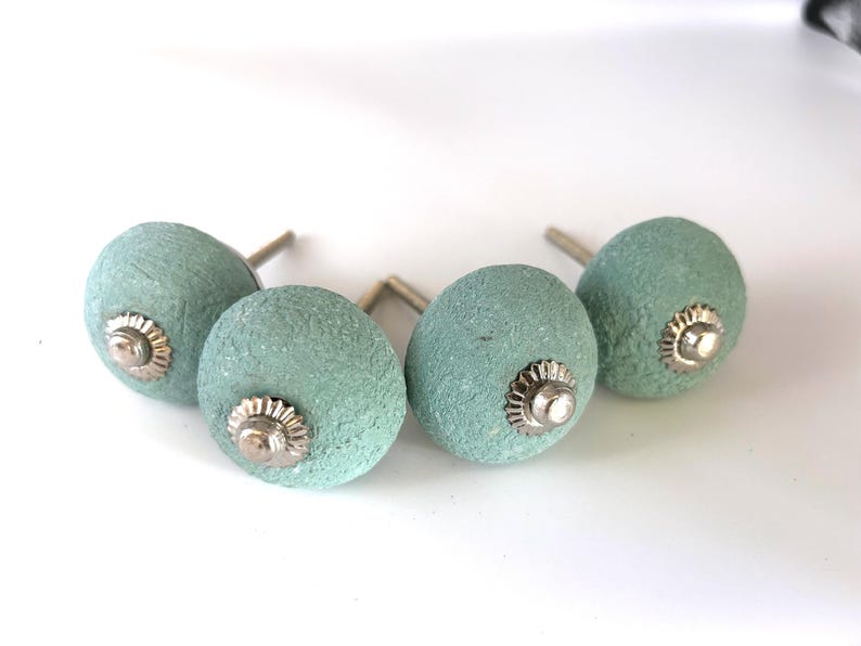 Puede incluir: Cuatro pomos de armario de color aguamarina con un acabado texturizado. Cada pomo tiene una base plateada y un centro decorativo plateado. Los pomos est&aacute;n dise&ntilde;ados para muebles y decoraci&oacute;n del hogar.