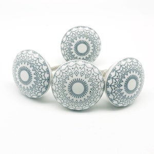 May include: Three white ceramic cabinet knobs with a gray mandala design.