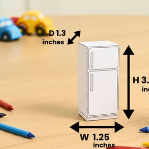 A papercraft miniature refrigerator with dimension overlays indicating height, width, and depth on a wooden surface.