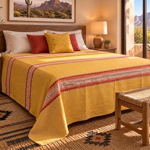 May include: A mustard yellow bedspread featuring a horizontal band with red, white, and grey geometric patterns. The bedding set includes two white pillows, two solid red pillows, and one yellow square pillow with a small repeating pattern.
