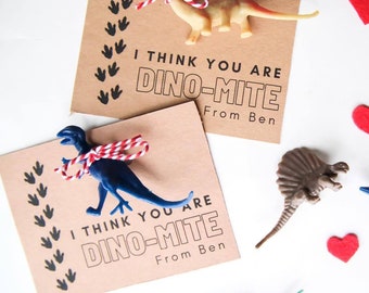 May include: Two brown cards with the text "I think you are Dino-mite" and a dinosaur toy attached to each card. The cards are surrounded by red felt hearts and various dinosaur toys.