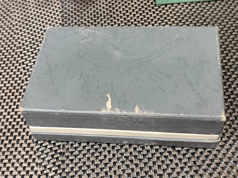 May include: A gray cardboard box with a white stripe around the edge. The box has a textured surface and appears to be slightly worn.