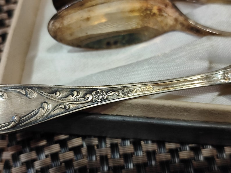 May include: Close-up of the back of a silver spoon with an ornate design and the inscription "Sterling 22/40".