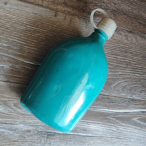 May include: A turquoise plastic water bottle with a white lid and a carrying handle.