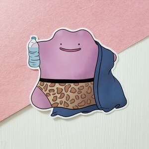 以下が含まれることがあります： 紫色の形をした漫画のキャラクターのステッカー。ヒョウ柄の下着と青いタオルを着用しています。キャラクターは水筒を持っています。ステッカーには白い縁があります。