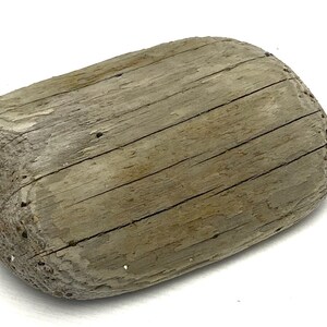 Op de afbeelding: Een verweerd, grijs houten drijfhoutstuk met een afgeronde vorm en een glad, getextureerd oppervlak.
