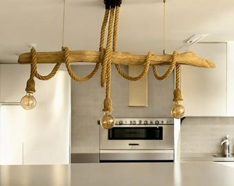 May include: A ceiling light fixture featuring a horizontal piece of light brown driftwood suspended by thick tan rope. Three light bulbs hang from the driftwood at varying lengths, each wrapped in matching rope at the socket base.