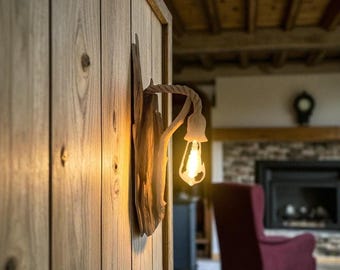 Puede incluir: Aplique de pared rústico hecho de madera flotante, con un brazo envuelto en cuerda y una bombilla decorativa. El aplique está montado en una pared de madera, añadiendo un toque natural y cálido al espacio. Mide unos 30 cm de alto.