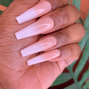 May include: Long, white ombre press-on nails with a nude base and a white tip. The nails are long and narrow, with a slight curve at the tip.