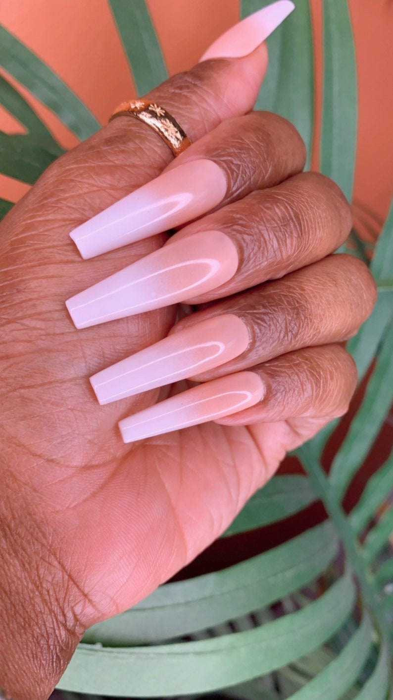May include: Long, white ombre press-on nails with a nude base and a white tip. The nails are long and narrow, with a slight curve at the tip.