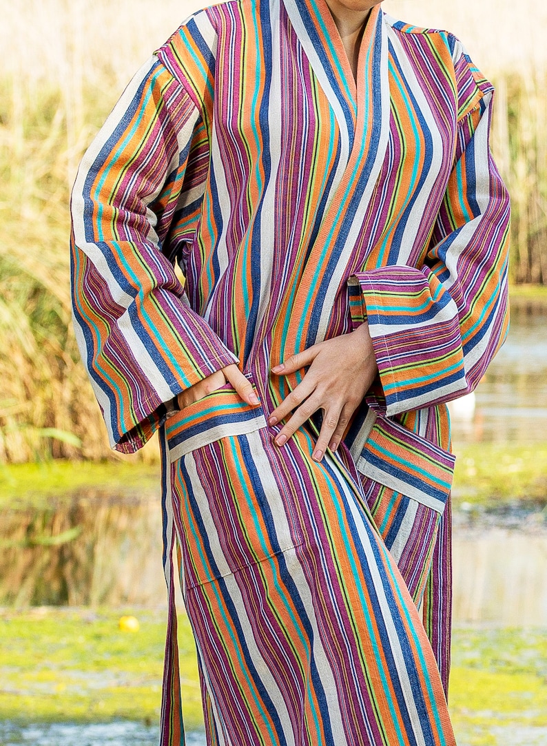 May include: A striped robe with a long sleeve and a sash tie. The robe is made of a soft, comfortable fabric and features a variety of colors, including orange, blue, purple, and white.