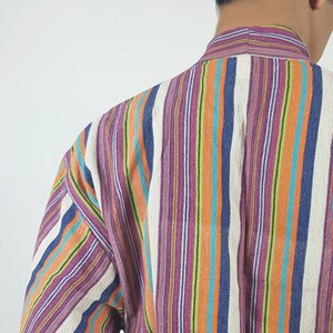 May include: A long-sleeved shirt with vertical stripes in shades of purple, orange, blue, green, and white.
