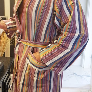 May include: A striped robe with a long sleeve and a tie belt. The robe is made of a soft, comfortable fabric and features a variety of colors, including orange, blue, purple, and white.
