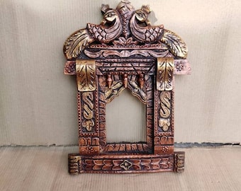 May include: A wooden picture frame with intricate carvings and gold accents. The frame features two peacocks with their tails spread out, creating a decorative archway.